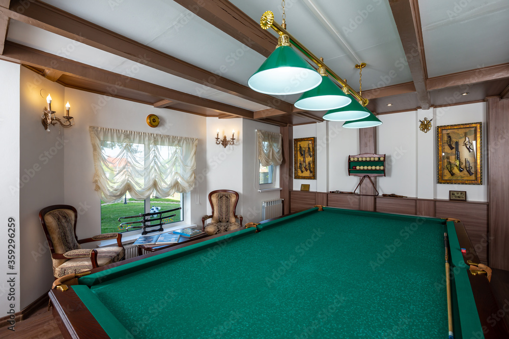 Billiard room interior. Green table for game. Old german style design. Brown wooden decor on the cei