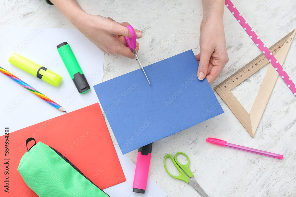 Student cutting paper sheet at table