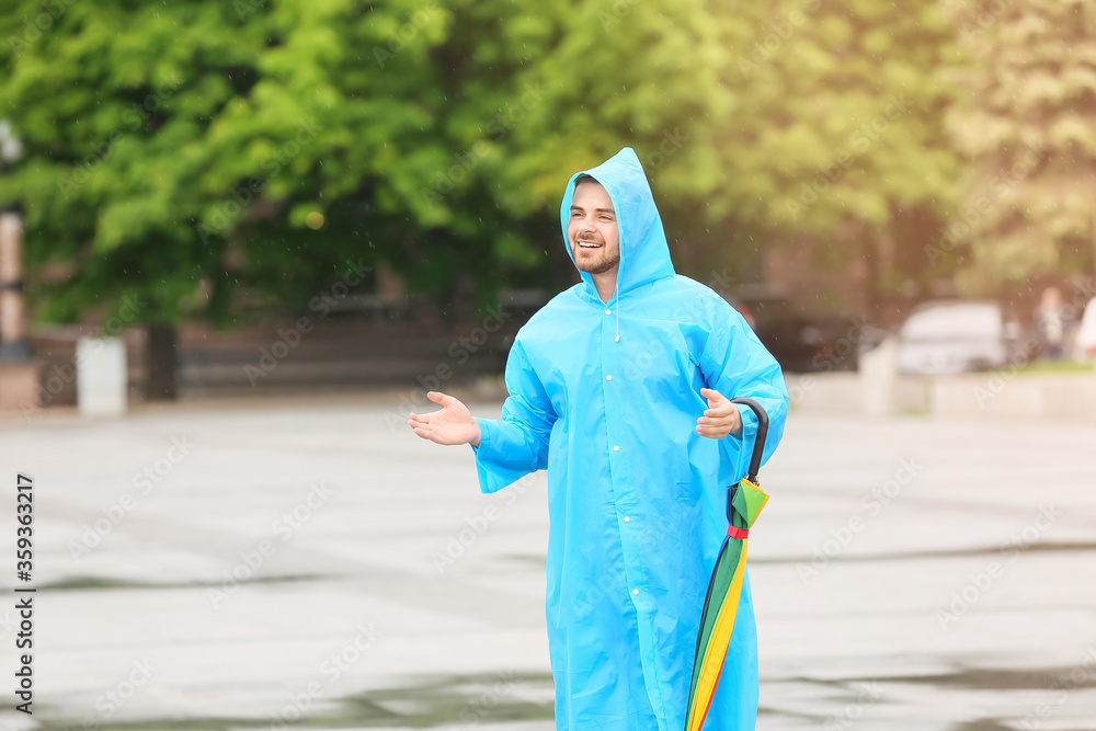 年轻人在户外打着雨伞，穿着雨衣