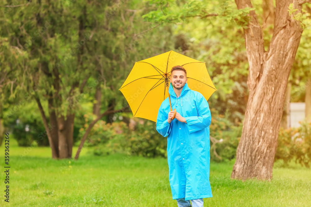 年轻人在户外打着雨伞，穿着雨衣