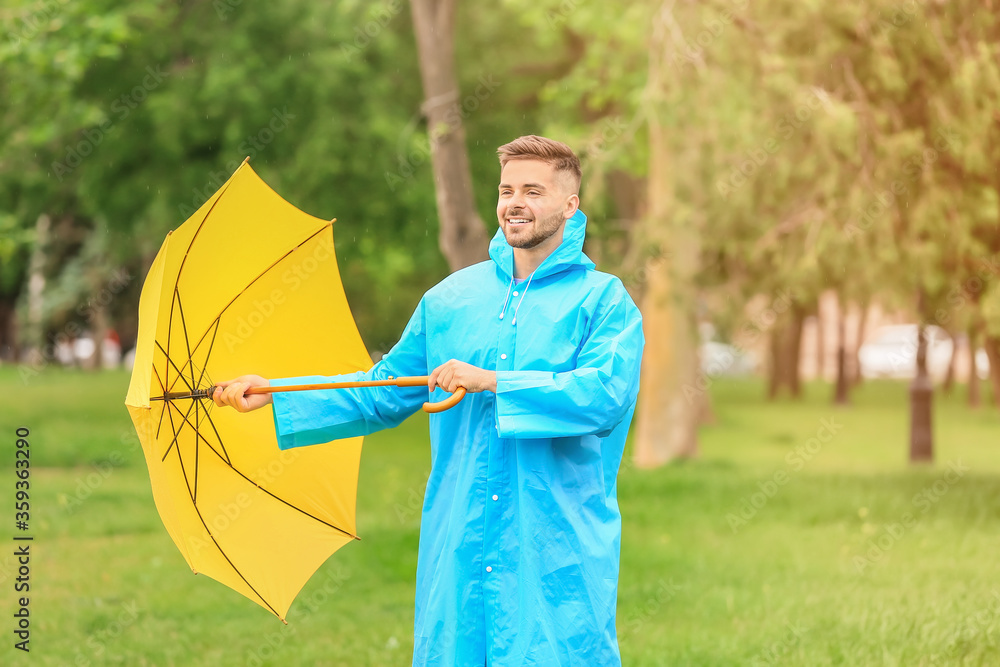 年轻人在户外打着雨伞，穿着雨衣