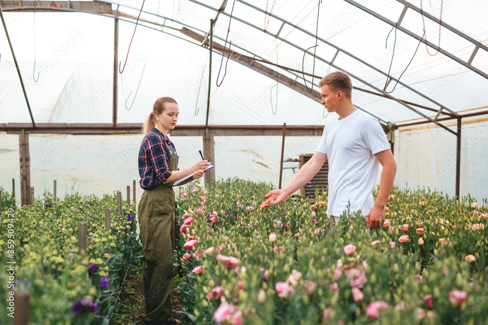 Attractive gardener young woman talking to a customer who wants to buy flowers. Entrepreneur of smal