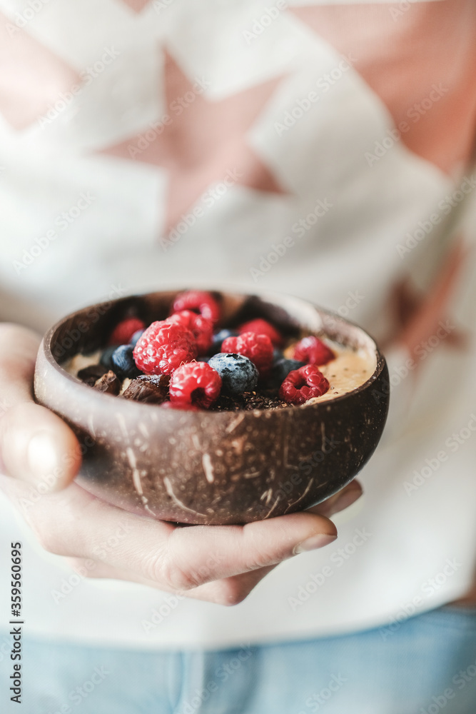 健康素食早餐碗。隔夜燕麦、芒果奶昔和椰子壳纳图新鲜浆果