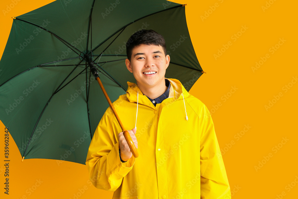 身穿雨衣、背景为彩色雨伞的亚洲年轻男子