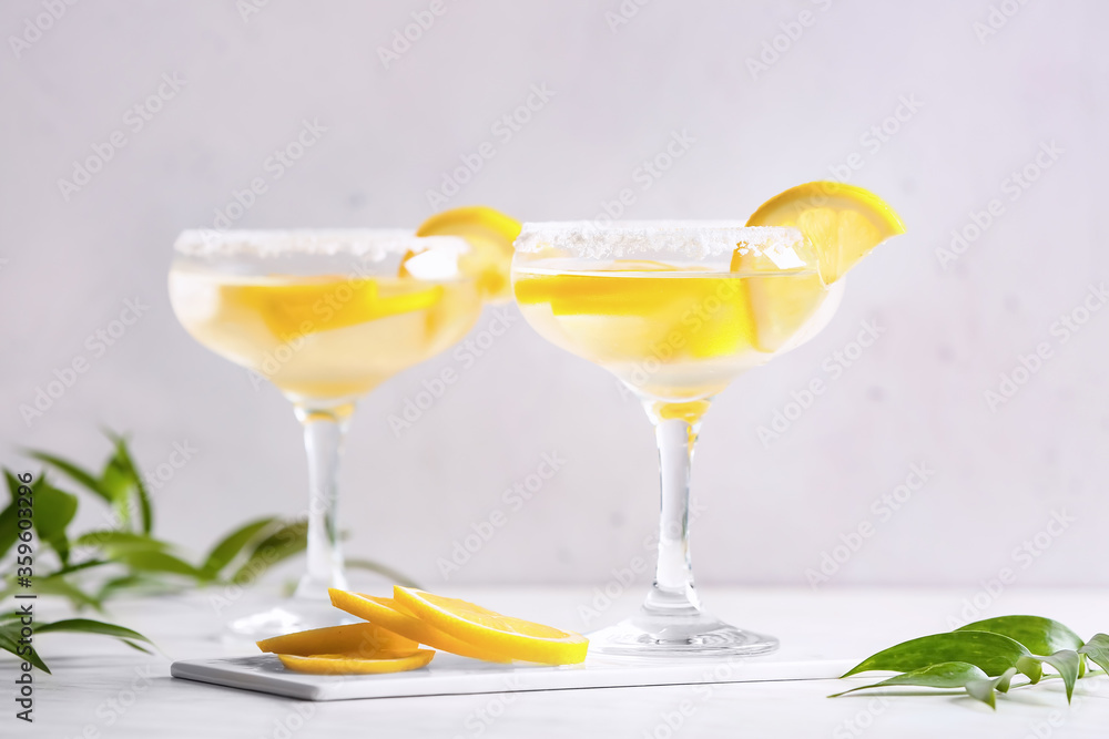 Glasses of tasty martini cocktail with lemon on light background