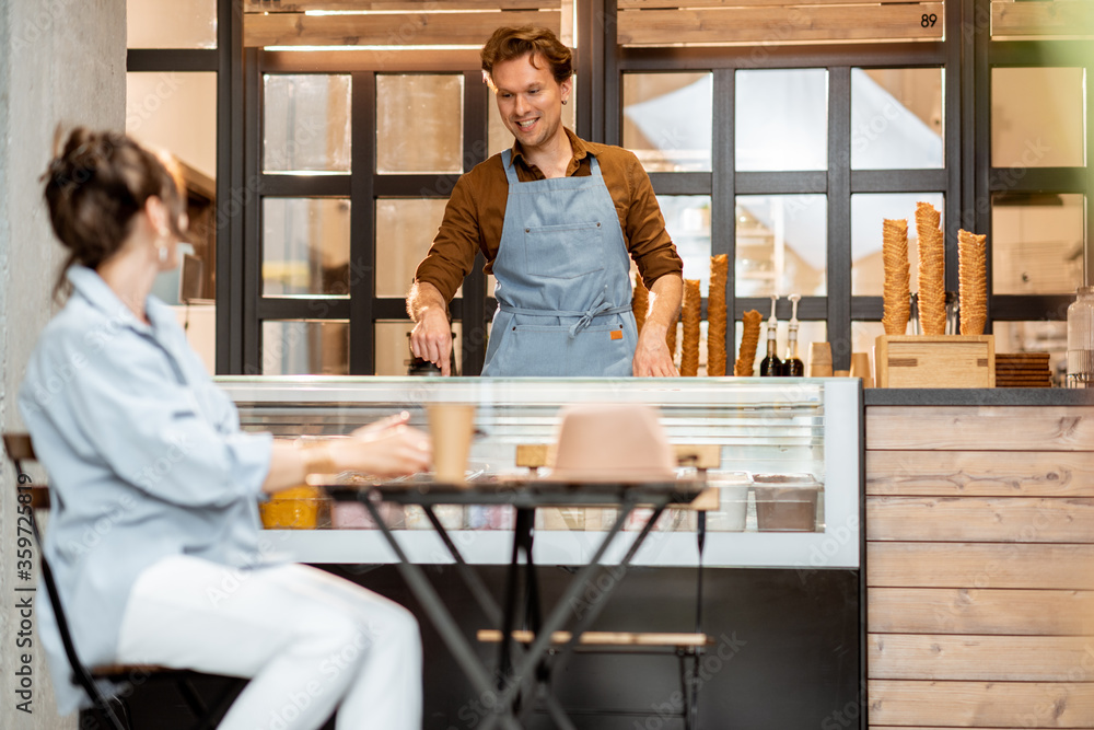 Handsome seller with female customer at the pastry shop or cafe