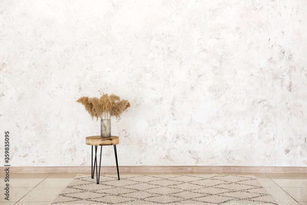 Table with vase near light wall in room