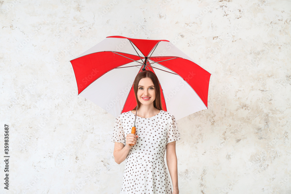 Beautiful woman with umbrella on light background