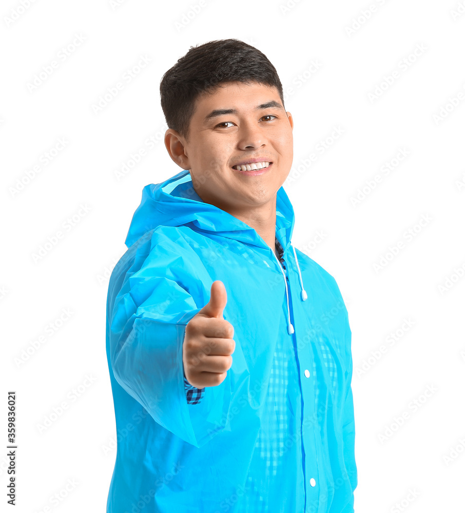 Young Asian man in raincoat showing thumb-up on white background