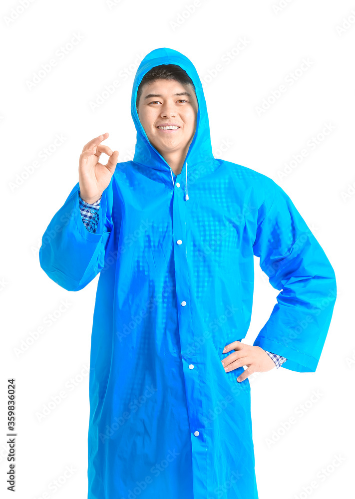 Young Asian man in raincoat showing OK on white background