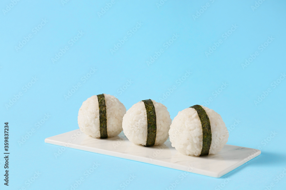 Plate with traditional Japanese onigiri on color background