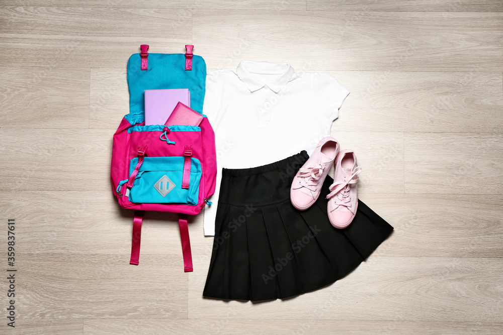 Stylish school uniform with backpack on wooden background