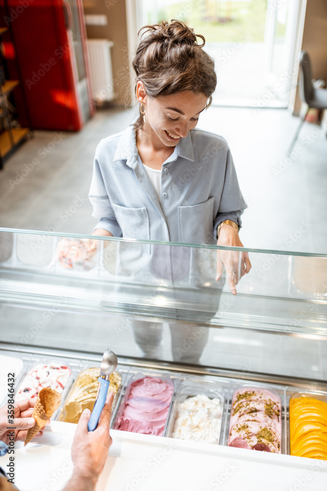 年轻女性客户选择冰淇淋口味，与卖家站在橱窗附近