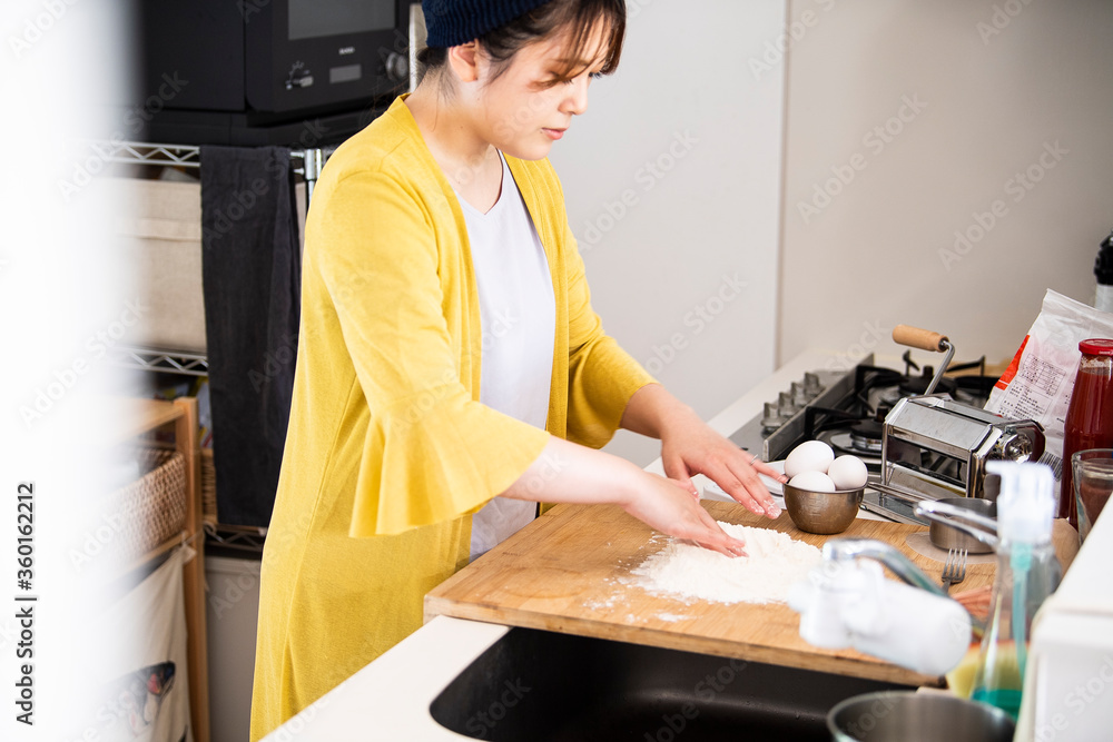 まな板に小麦粉を広げる調理中の女性
