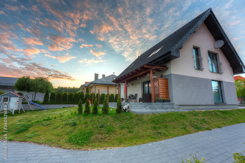 A modern single family house with a garden at sunset