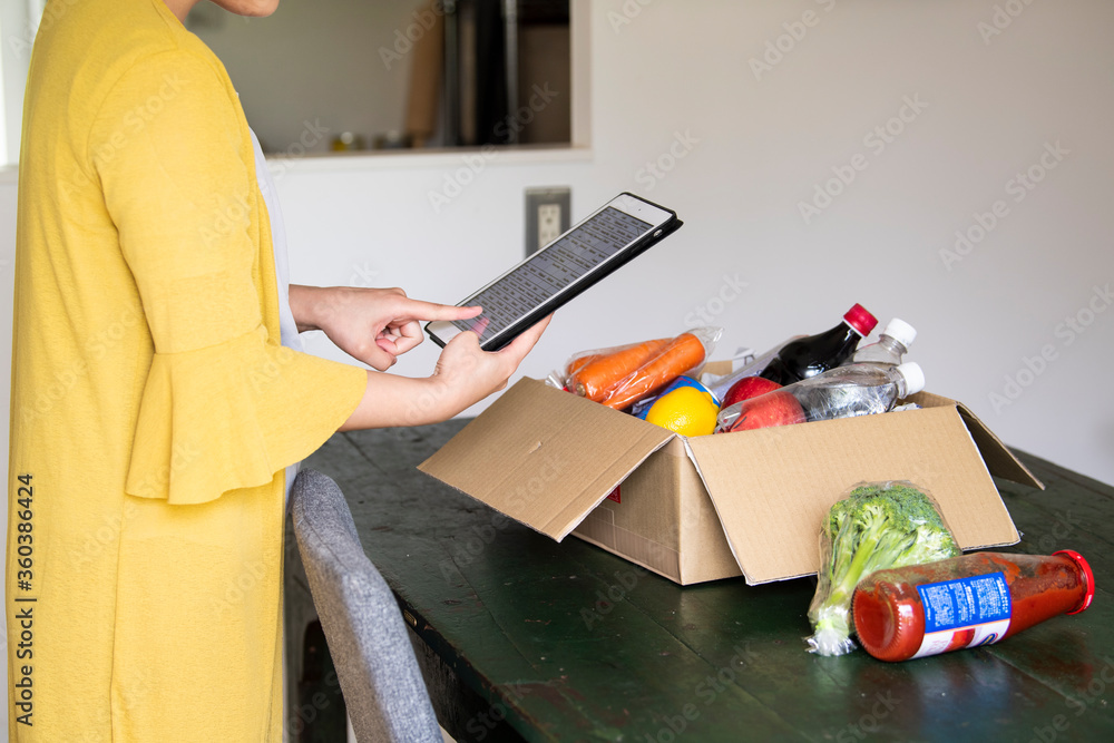 宅配注文した食品の情報をタブレットで確認する女性
