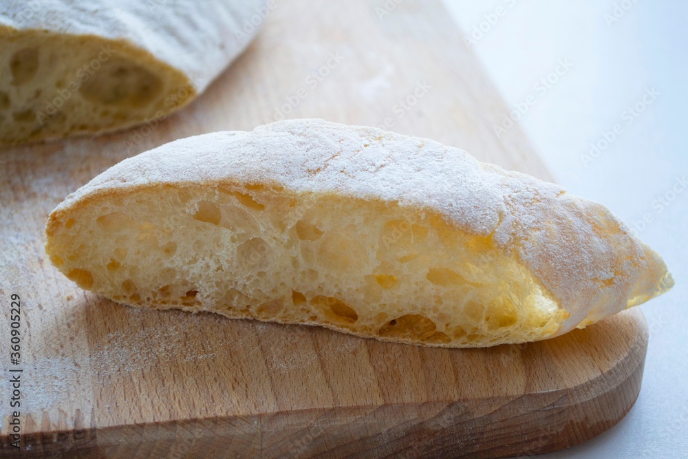 Composition of pieces of homemade crispy baguette on a wooden board, in daylight. A piece in the for