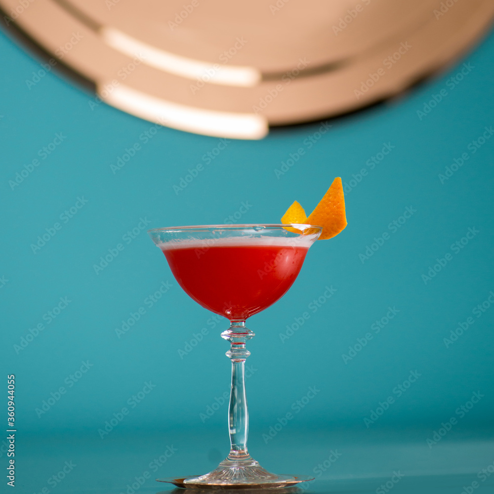 Ready-made cocktail in red with orange zest on the background with place for text. Mixology