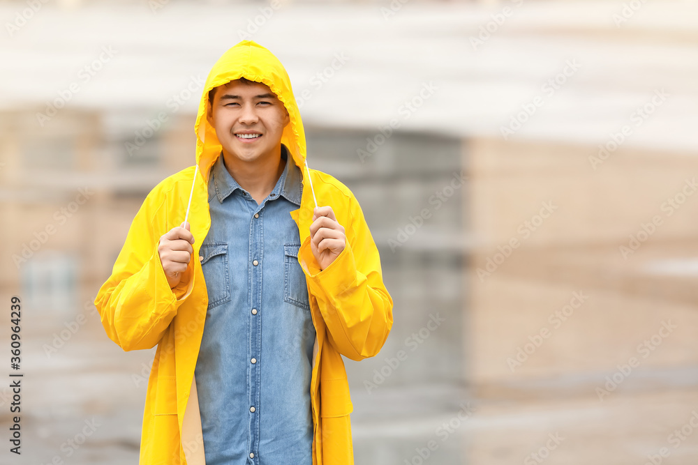 城市街道上穿着雨衣的亚洲年轻人