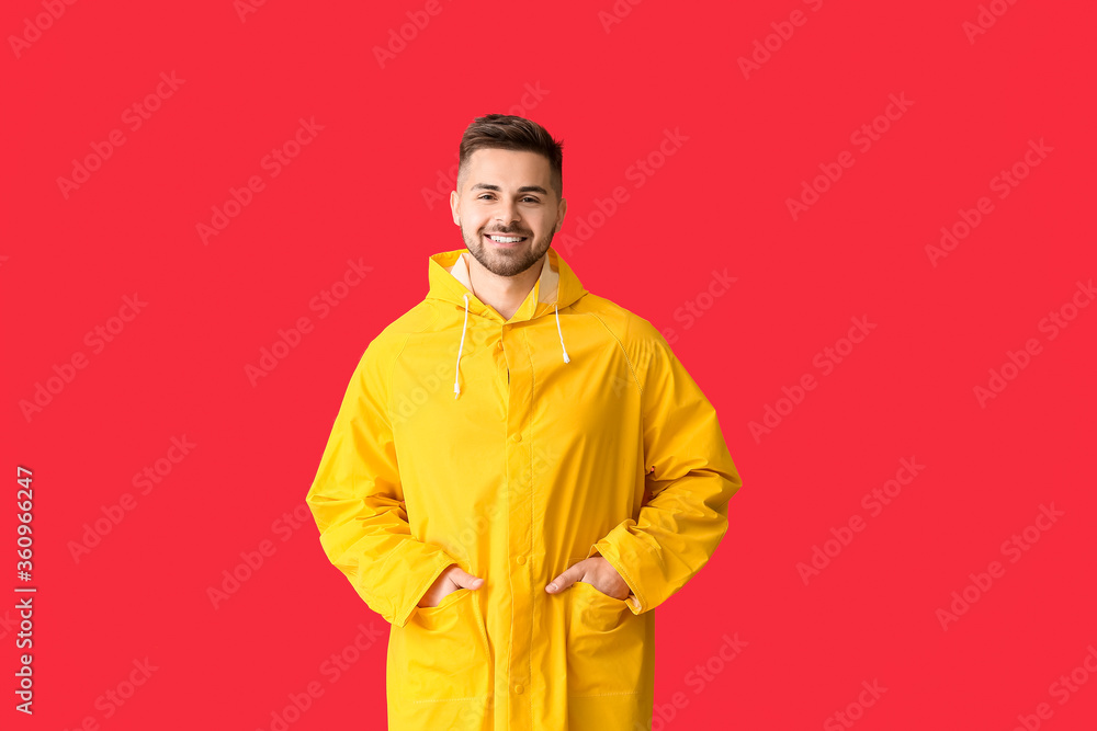 Young man in raincoat on color background