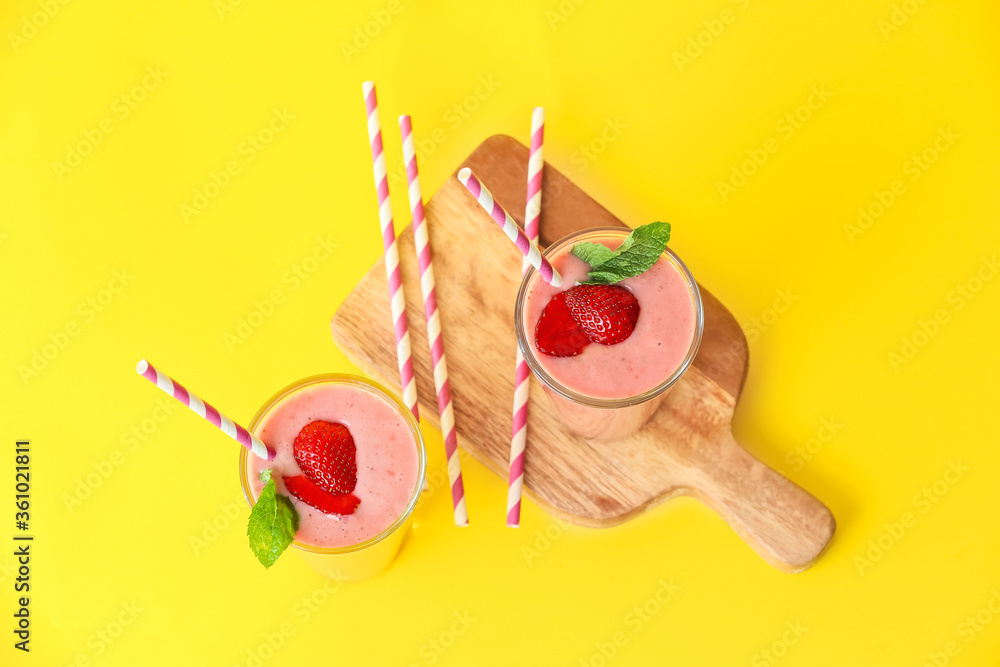 Glasses of tasty strawberry smoothie on color background