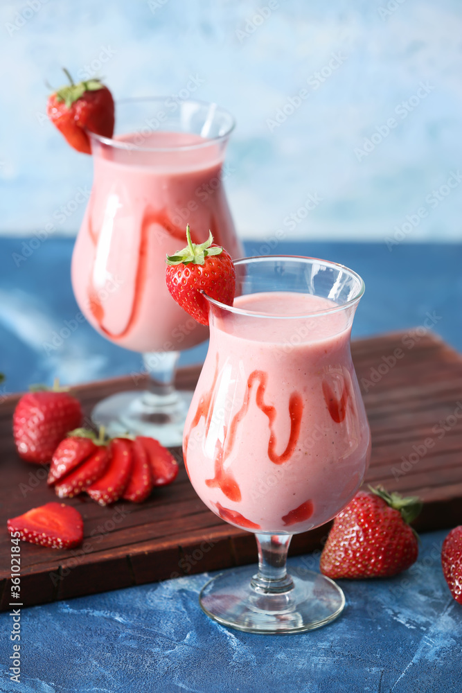 Glasses of tasty strawberry smoothie on color background