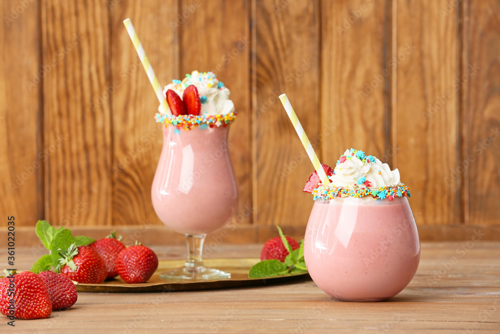 Glasses of tasty strawberry milkshake on table