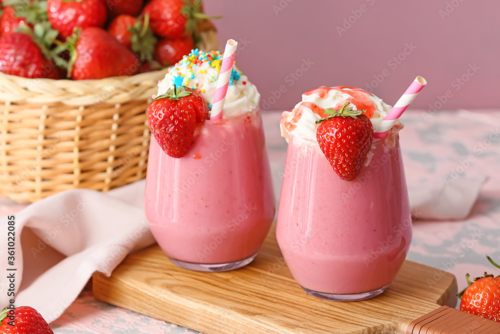 Glasses of tasty strawberry milkshake on table