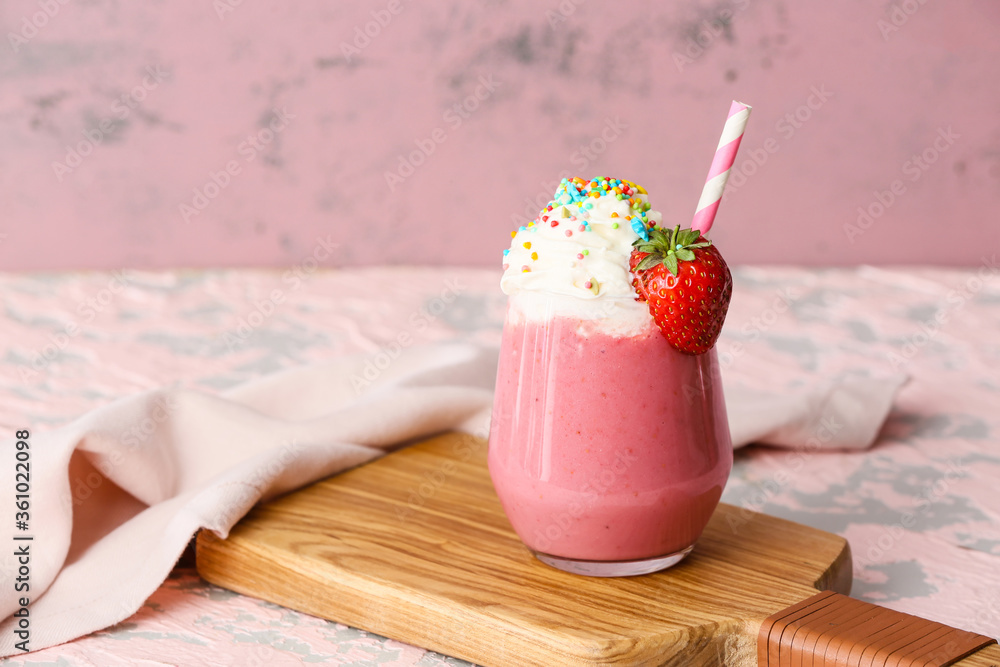 Glass of tasty strawberry milkshake on color background