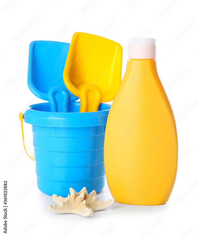 Sunscreen cream with beach sand toys on white background