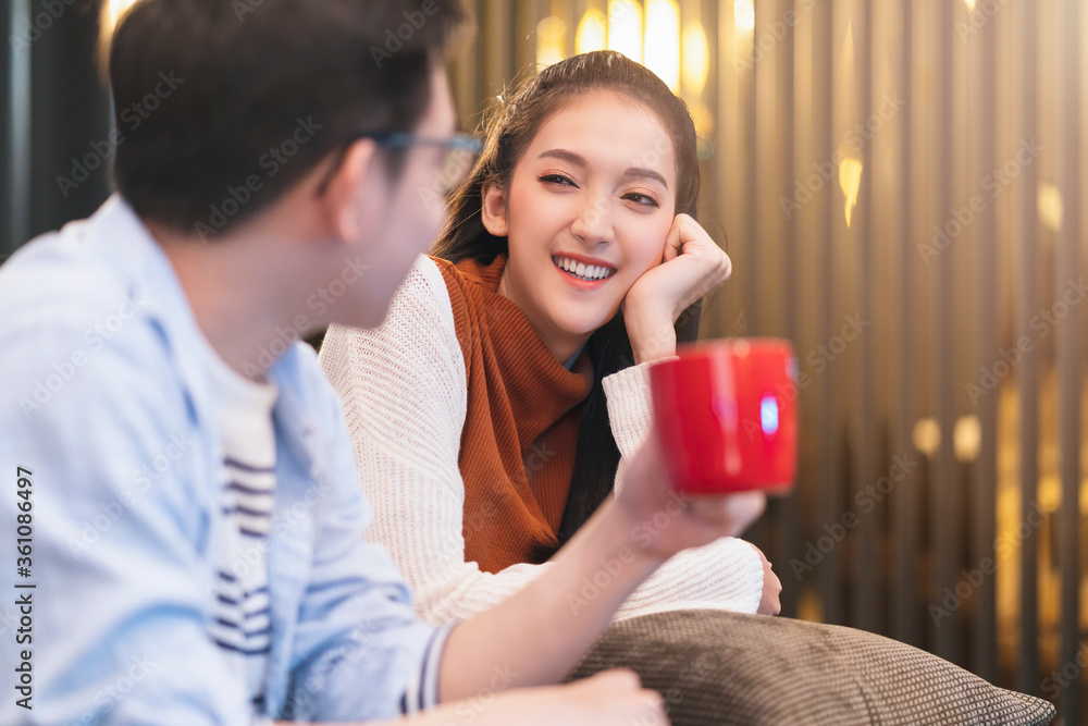 幸福的年轻亚洲夫妇结婚家庭享受电视节目和良好的交谈拥抱在一起