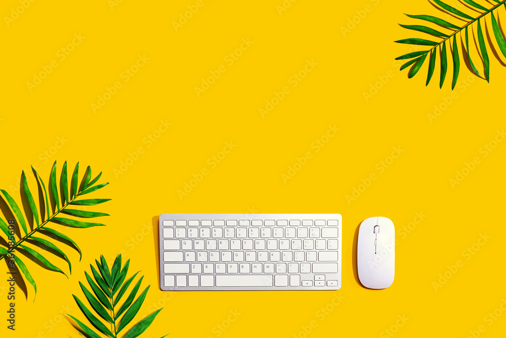 Computer keyboard and mouse with tropical leaves