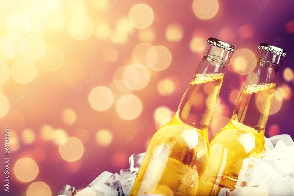 Bottles of cold and fresh beer with ice on bokeh background