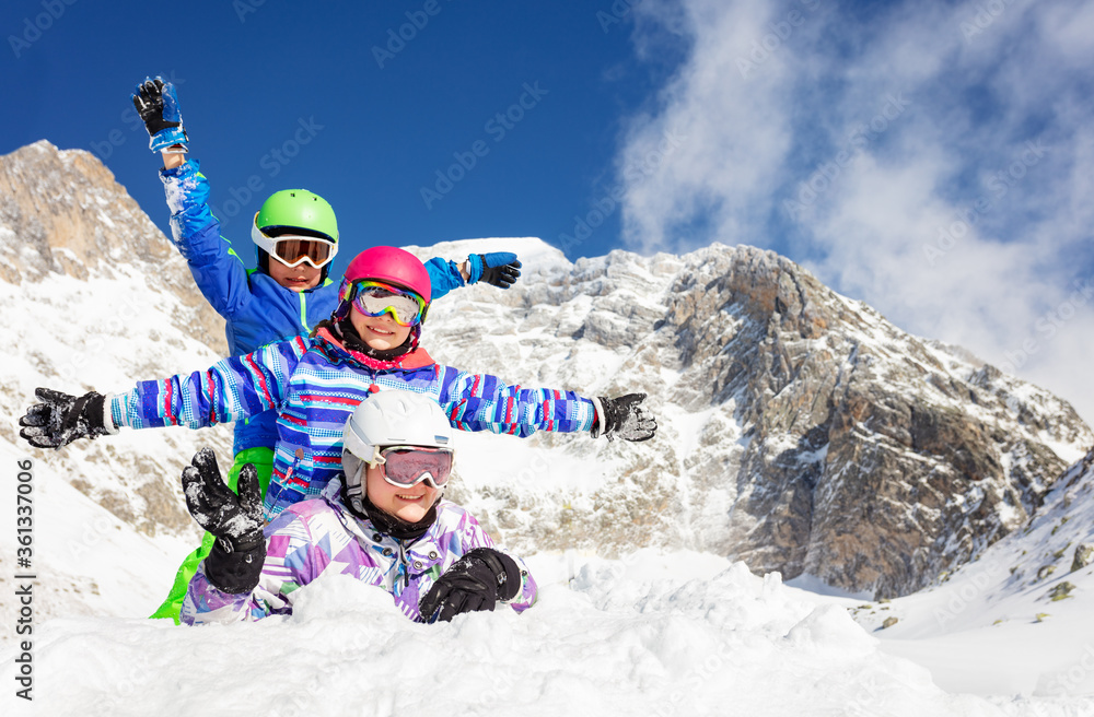 三个快乐女孩的肖像躺在雪地上，面带微笑，与群山挥手