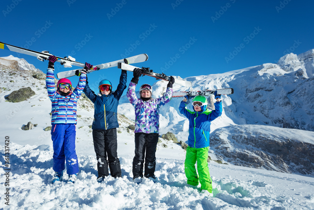 一群孩子穿着彩色衣服，戴着头盔，在空中举行山地滑雪快乐寒假