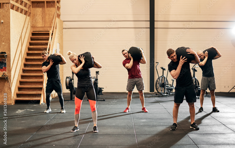 People working out with weight bags together at the gym