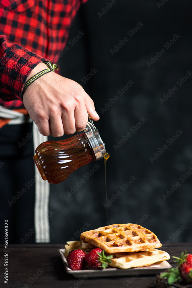 男子在华夫饼干甜点上加蜂蜜