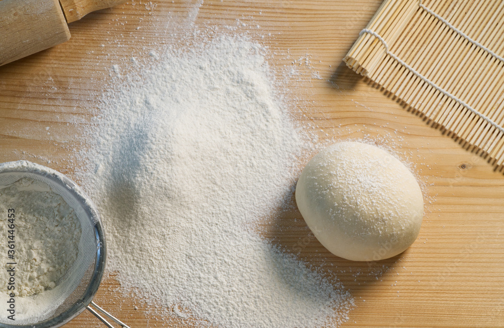 Flour and dough on board, sieve and finished dough on a cutting board, cooking