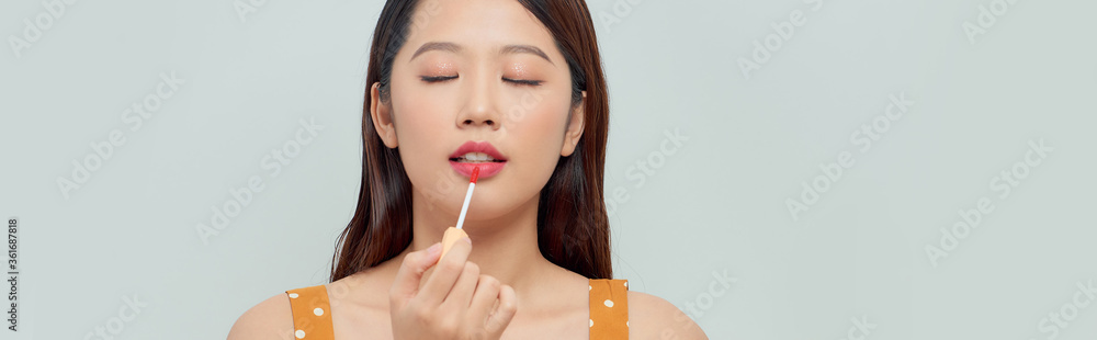 Close up portrait of a beautiful young woman with make up artist applying lip gloss