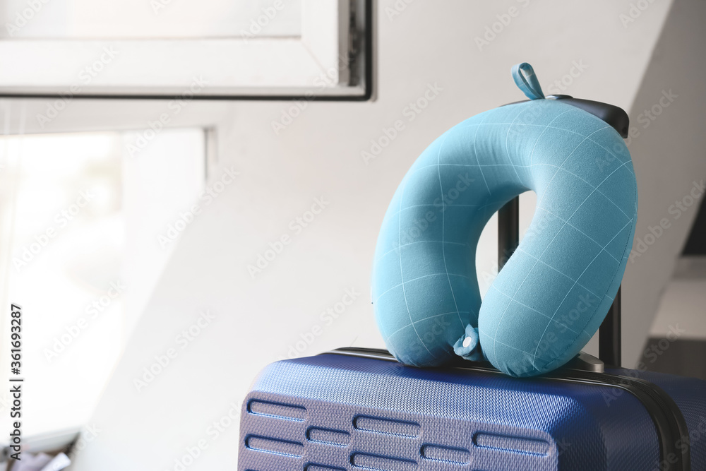 Packed suitcase and travel pillow in room