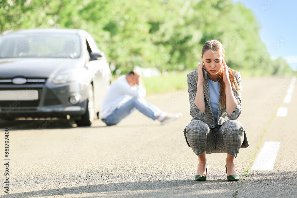 年轻女子在路上靠近破碎的汽车