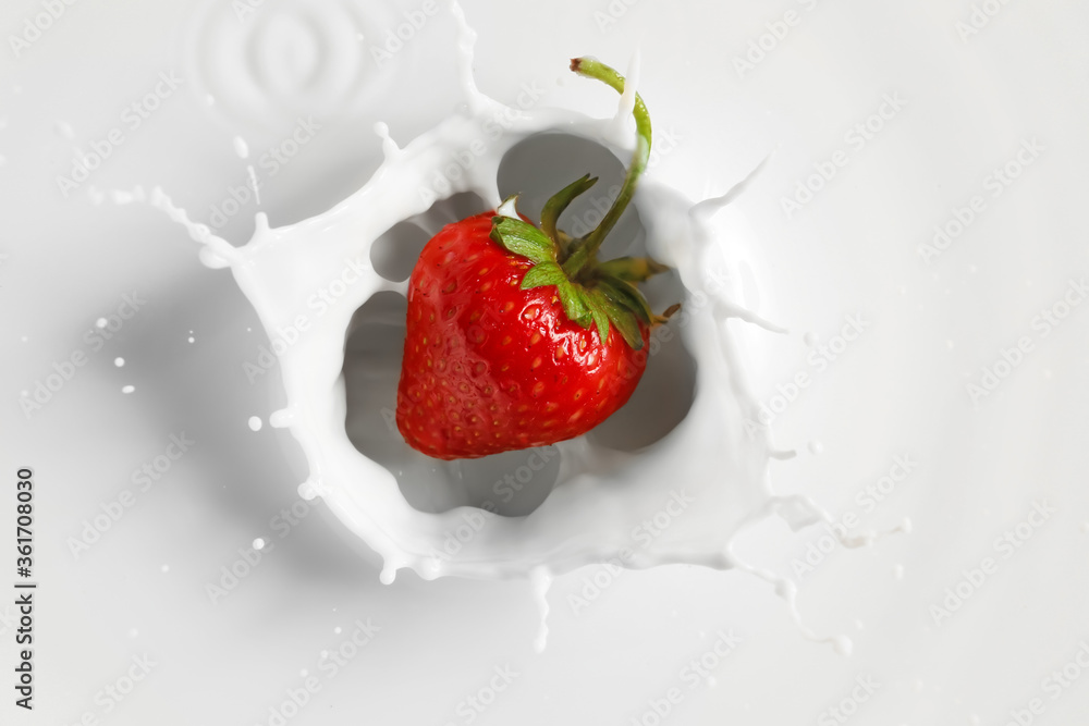 Falling of fresh strawberry into milk