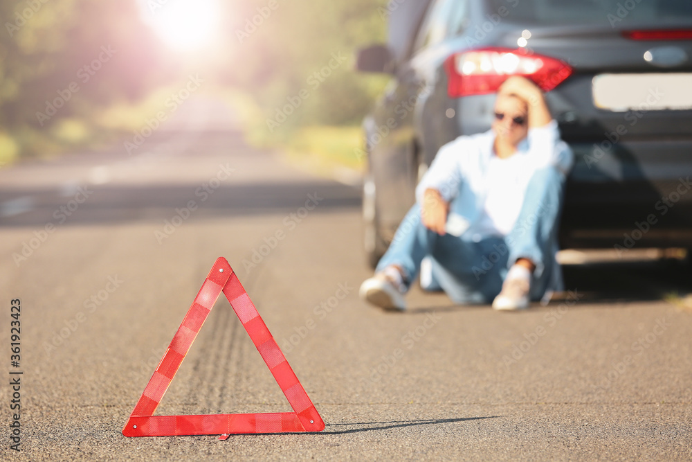 紧急停车标志和道路上靠近破碎汽车的男子