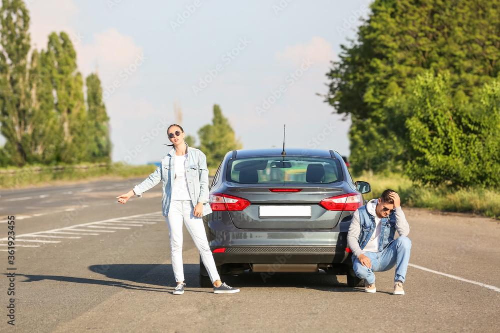 年轻夫妇在路上靠近破碎的汽车