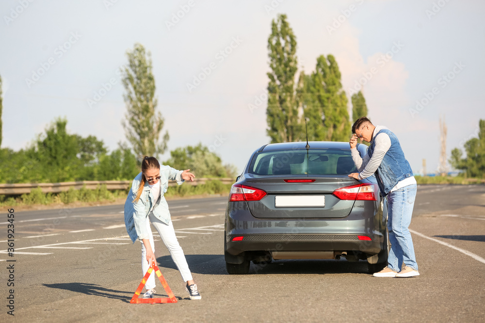 一对年轻夫妇在路上靠近一辆坏车