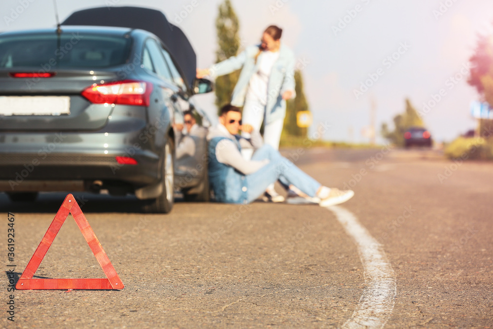 道路上破碎汽车附近的紧急停车标志和情侣