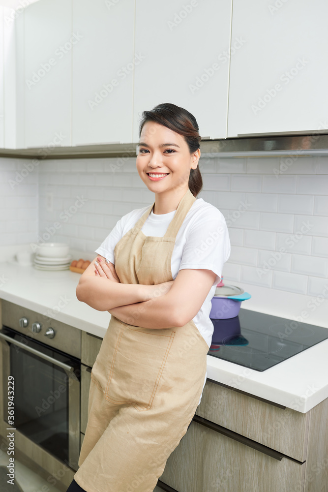 年轻女子交叉双臂站在厨房背景下的肖像