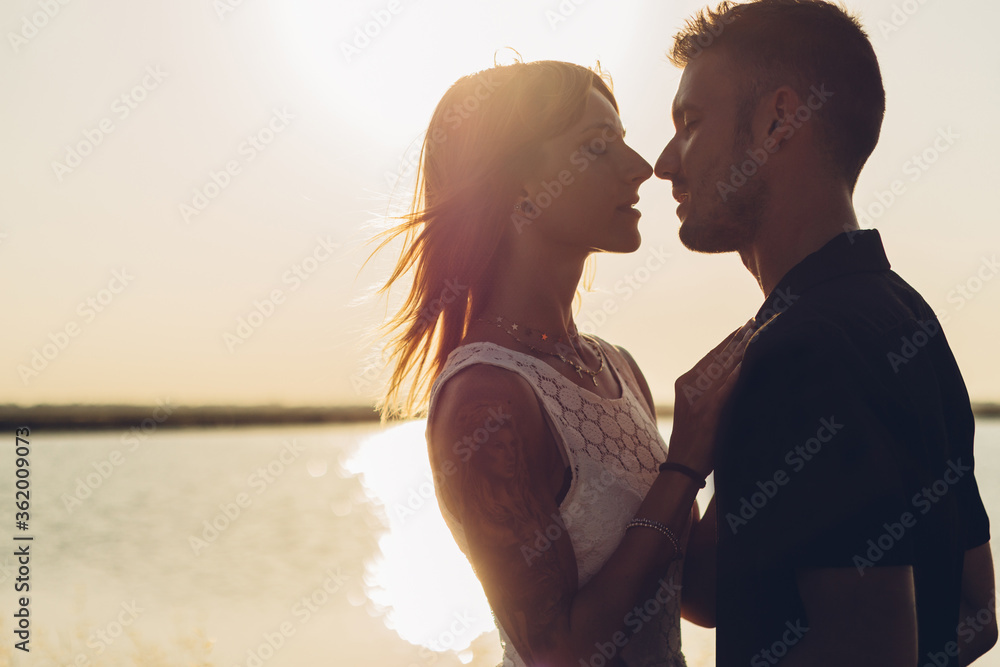 Romantic young couple kissing over beach sunset background