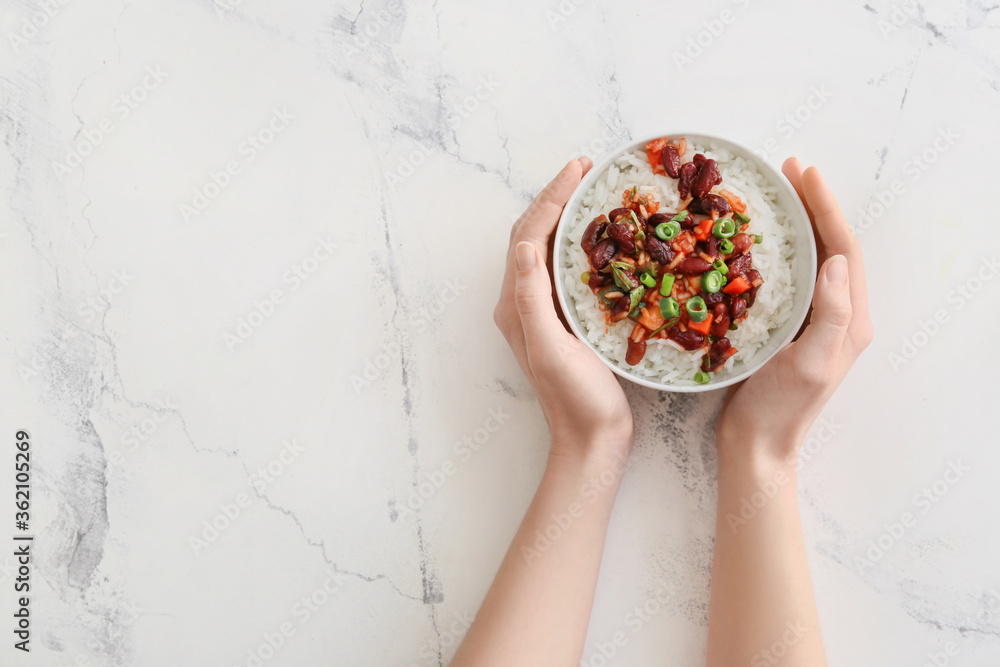 白色背景的碗里有美味的米饭和豆子的女性手，俯视图