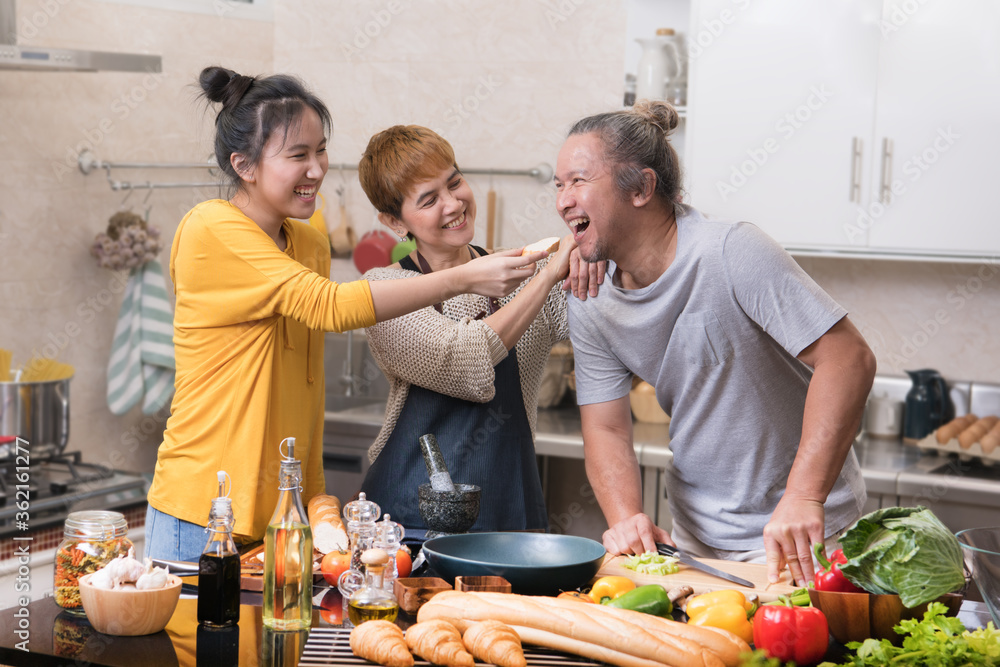 快乐的亚洲家庭，母亲、父亲和女儿在厨房烹饪，一起制作健康食品